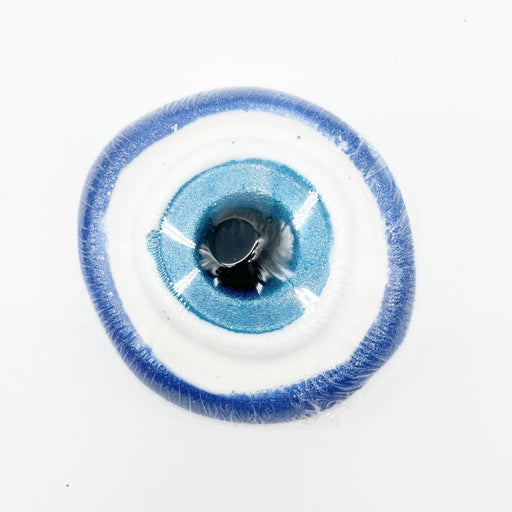 A single circular evil eye bath bomv with a blue and white design, shown on a plain white background.