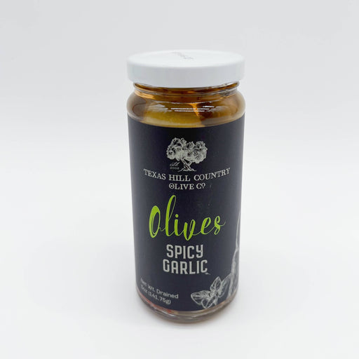 Jar of Texas Hill Country Olive Co. Spicy Garlic Olives on a white background